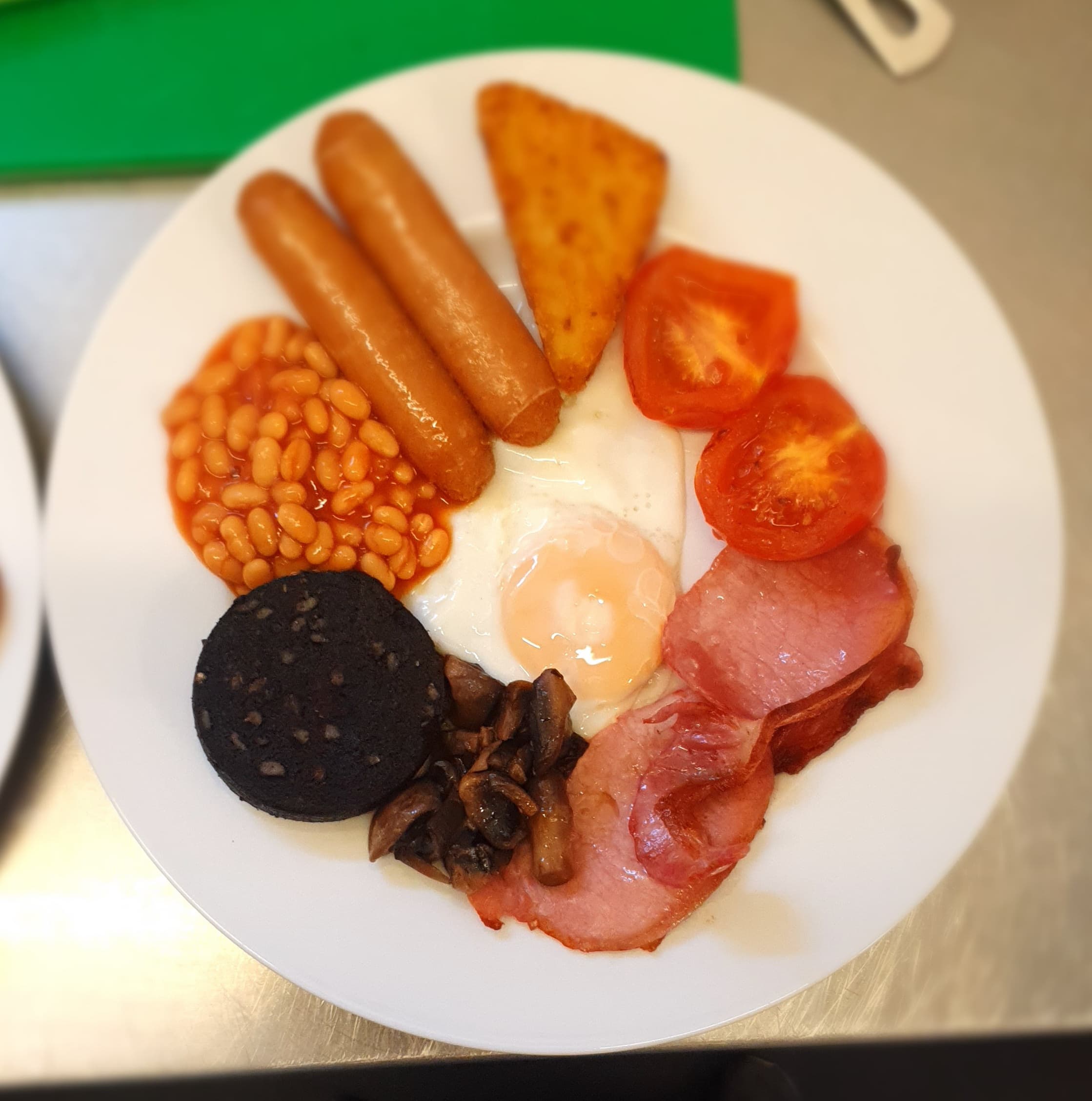 Photo of cooked breakfast, including egg, bacon, blackpudding, tomatoes, mushrooms, eggs